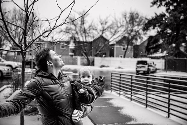 smiling adult carrying a smiling child outside on a snowy winter day